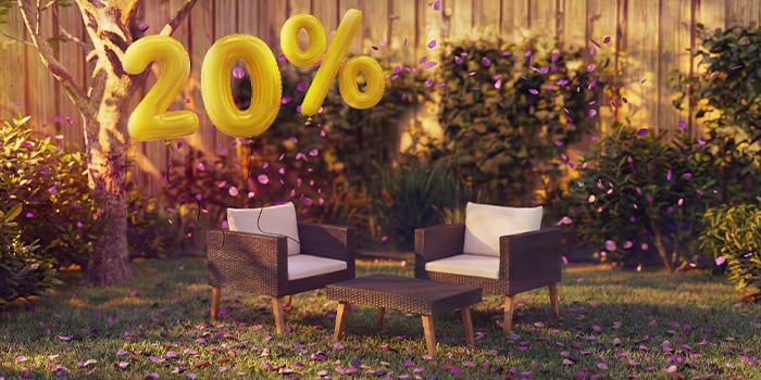 Outdoor-Bambus-Loungesofa mit grauen Kissen und passendem Couchtisch in einem Gartensetting, umgeben von rosa Konfetti und goldenen 20%-Rabatt-Ballons, die saisonale Angebote für Outdoor-Loungemöbel bewerben.