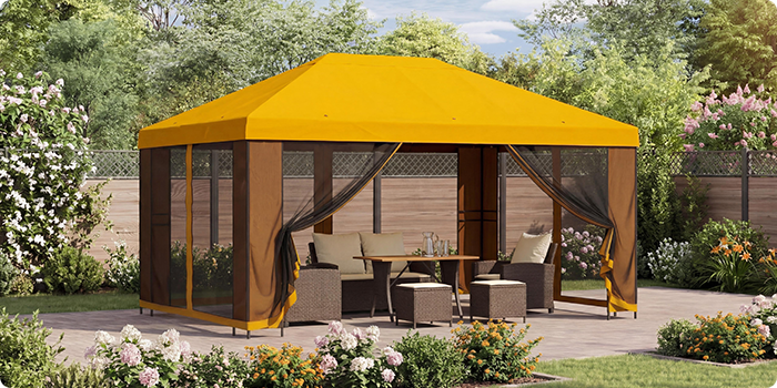 Gelber Gartenpavillon mit Netzvorhängen, der eine Sitzgruppe mit Tisch auf einer Terrasse in einem sonnigen Garten mit blühenden Pflanzen überdacht.
